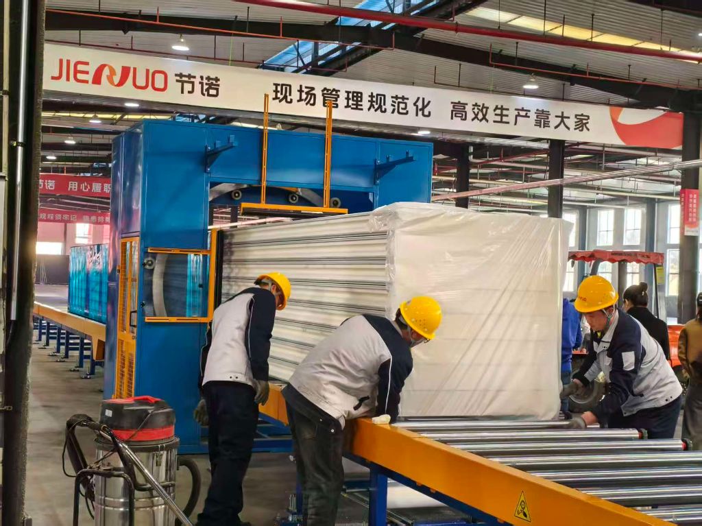 现代化生产流水线整齐规范，夹芯板在智能设备上高效流转，工人规范作业，整体生产高效有序。